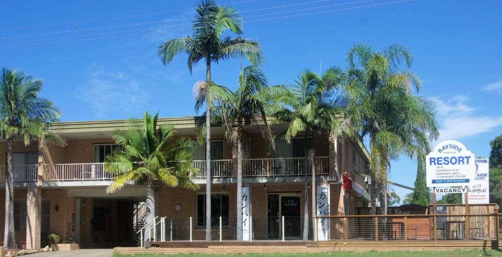 un edificio con palmeras delante en Huskisson Bayside Resort, en Huskisson