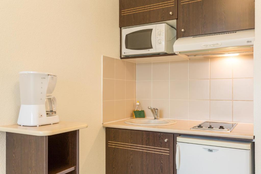 a small kitchen with a sink and a microwave at City Résidence Bordeaux Centre in Bordeaux