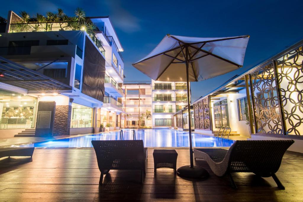 a patio with an umbrella and chairs and a pool at The Peak in Chanthaburi