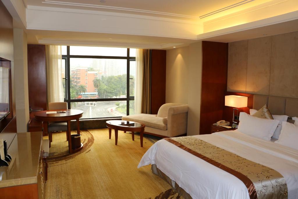 um quarto de hotel com uma cama e uma cadeira e uma janela em Rongjiang Hotel em Jieyang