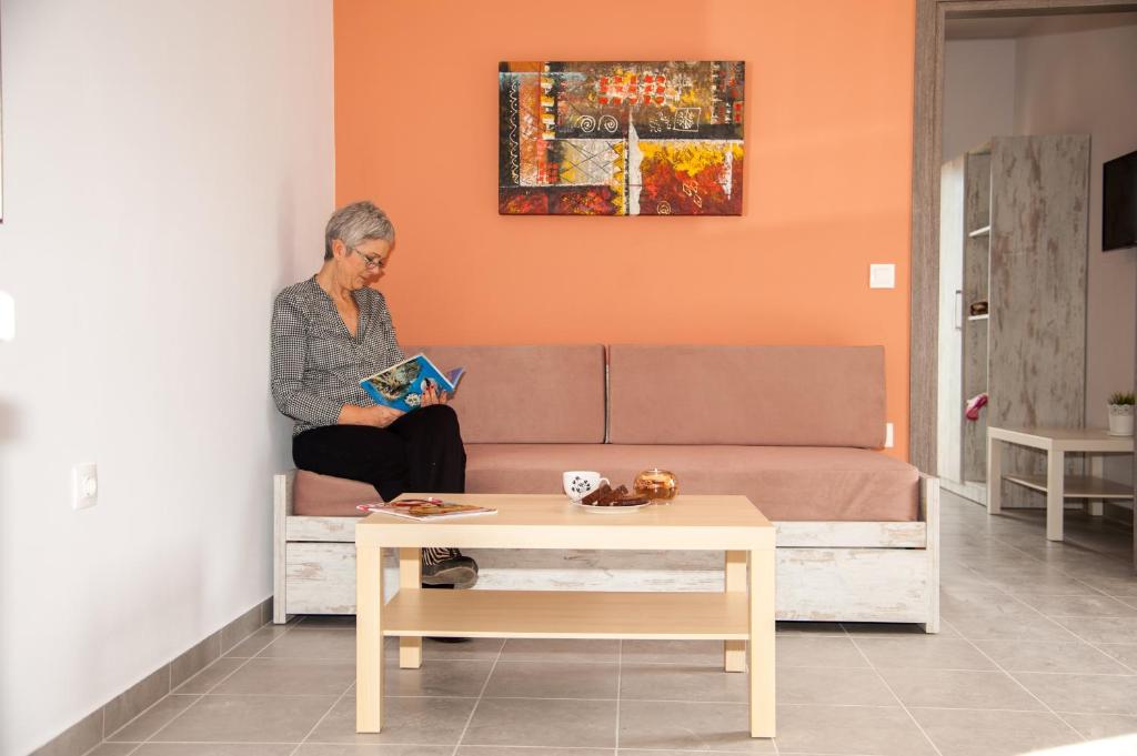 Kobieta siedząca na kanapie czytająca książkę w obiekcie Efrilias Studios & Apartments w mieście Kisamos
