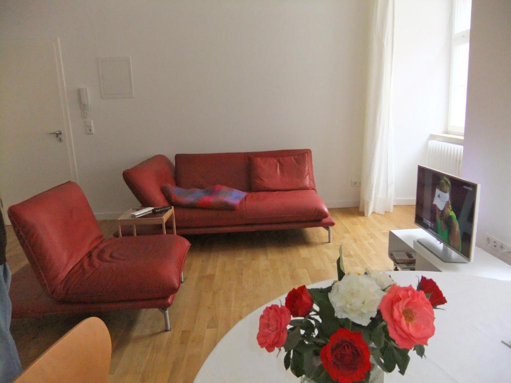 Palais am Schlossplatz في ميرسبرغ: غرفة معيشة مع أريكة حمراء وطاولة مع زهور