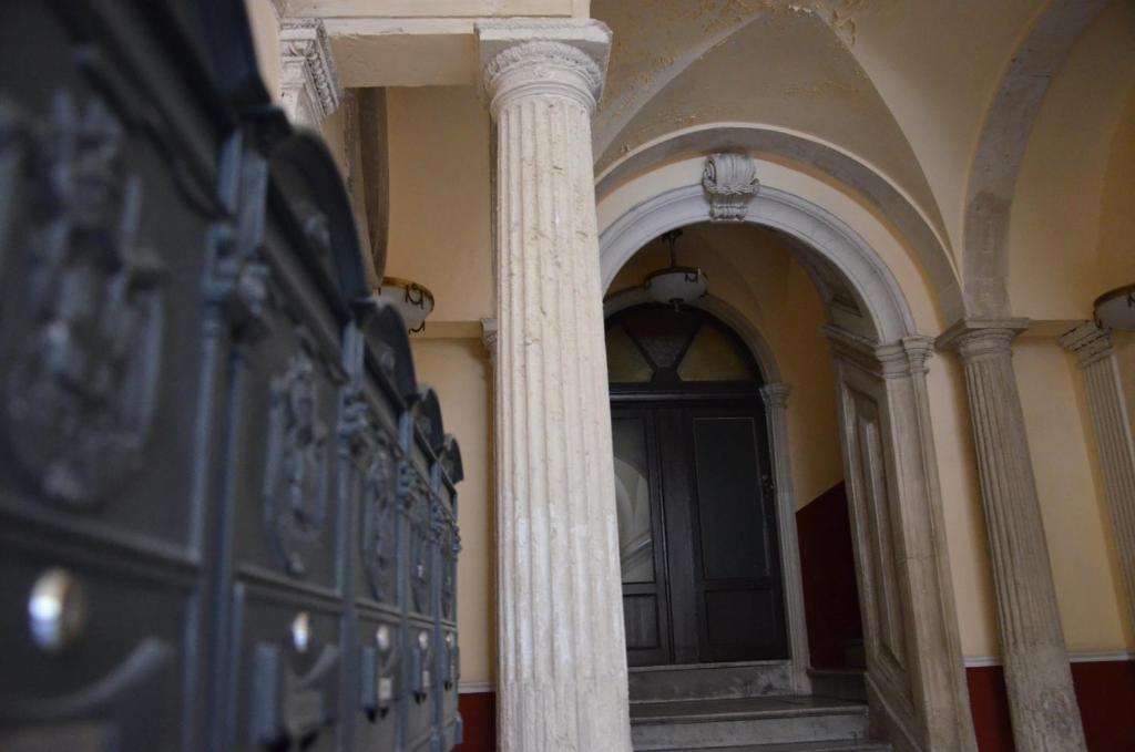 a pillar in a room with a door and an archway at B&B Chapo in Catania