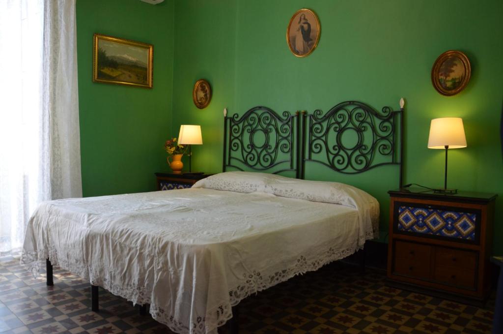 a bedroom with a bed with green walls and two lamps at B&B Chapo in Catania