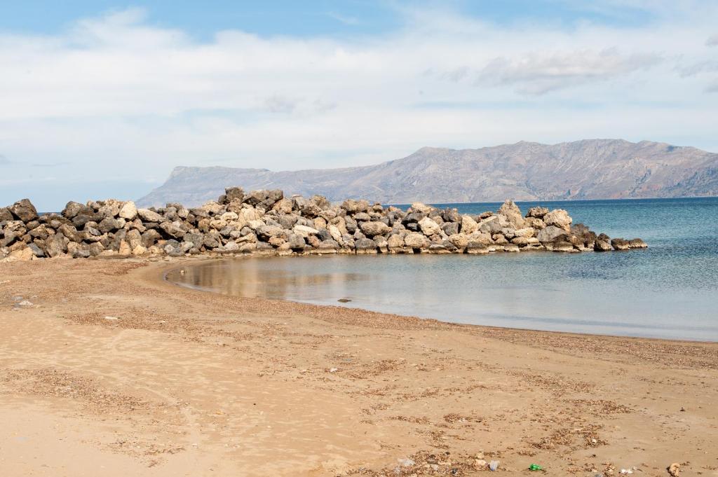 a beach with a pile of rocks in the water w obiekcie Efrilias Studios & Apartments w mieście Kisamos