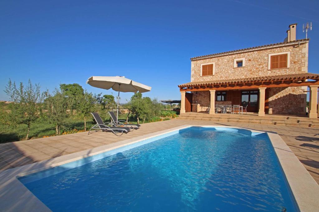 a villa with a swimming pool in front of a house at S'hort den Vadell in Campos