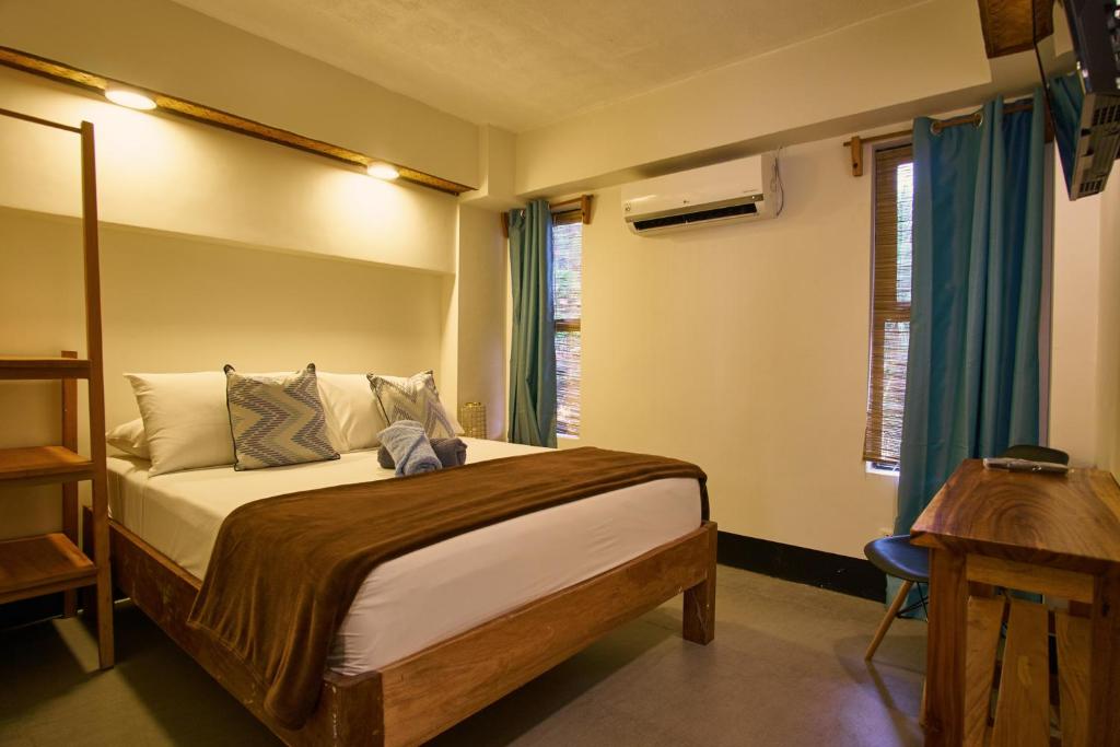 a bedroom with a bed and a desk and window at Amakan - El Nido Palawan in El Nido