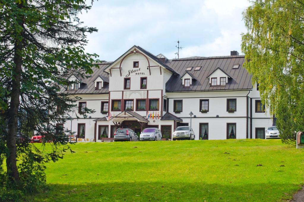 um grande edifício branco com carros estacionados em frente em Hotel Start em Spindleruv Mlyn