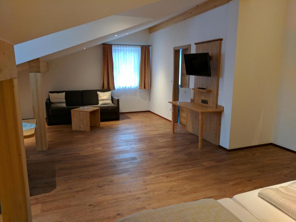 ein Wohnzimmer mit einem Sofa und einem TV in der Unterkunft Gasthaus Weingast in Bad Feilnbach