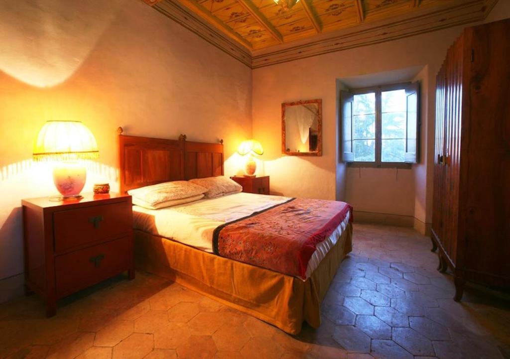 een slaapkamer met een bed, een lamp en een raam bij Appartamenti Lais in Sipicciano in Sipicciano