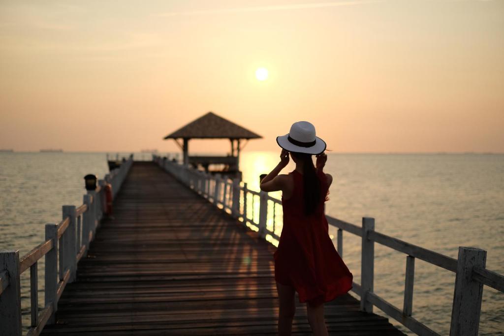 Kobieta stojąca na molo patrząca na zachód słońca w obiekcie Villa at Casalunar Bangsaen w mieście Bang Saen