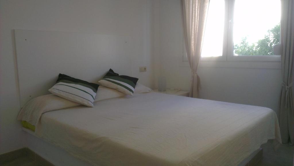 Cama blanca en habitación con ventana en Apartaments Josep Pla, en Roses
