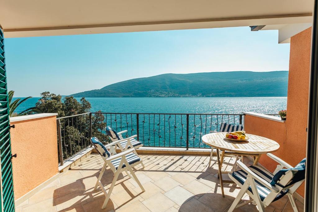 einen Balkon mit einem Tisch und Stühlen sowie Blick auf das Wasser in der Unterkunft Boka Apartment 1 in Herceg-Novi