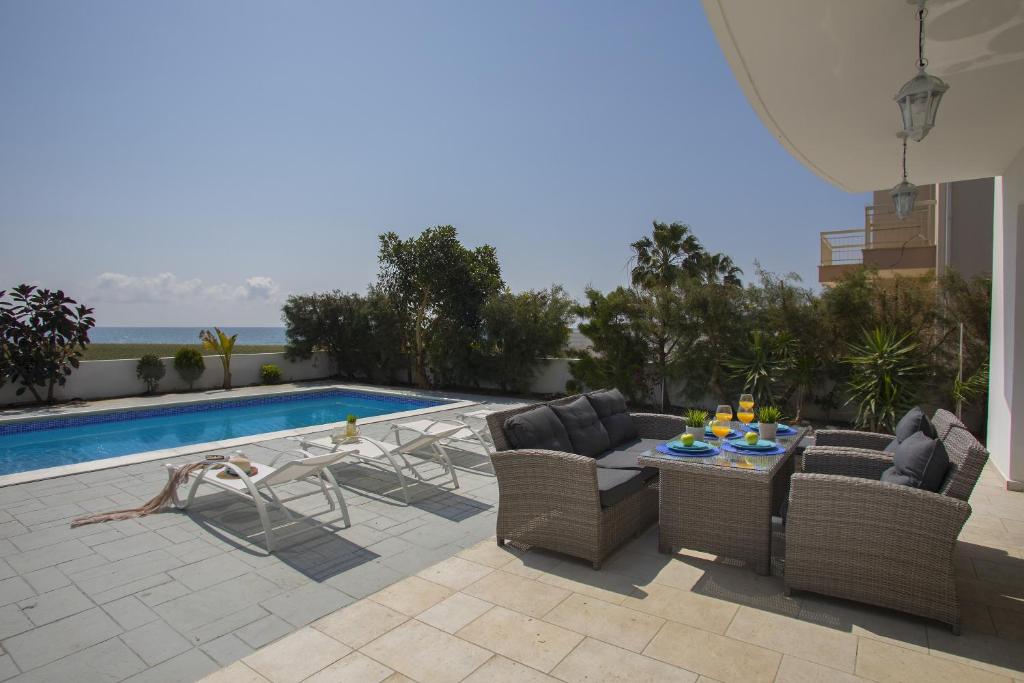 d'une terrasse avec des chaises et une table à côté de la piscine. dans l'établissement Villa Iris, à Mazotos