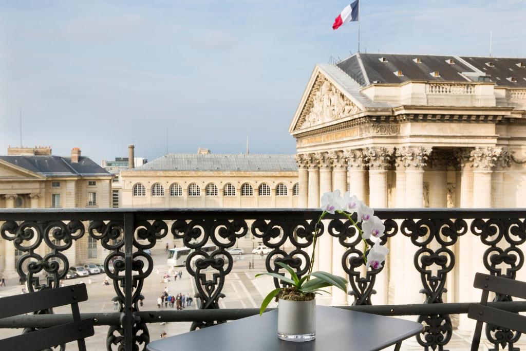 a balcony with a table and a building with a flag at Hôtel Les Dames du Panthéon in Paris