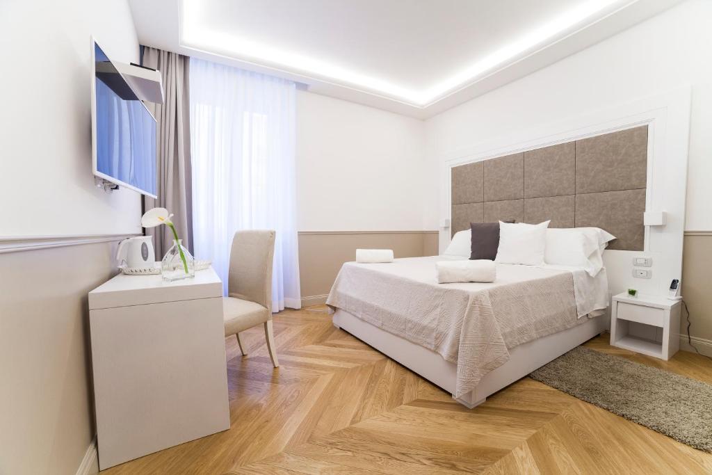 biała sypialnia z łóżkiem i telewizorem w obiekcie Margherita Suites w Rzymie