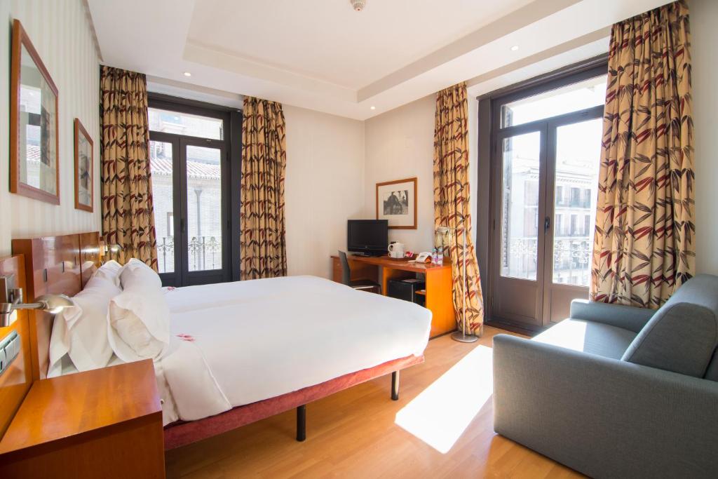 
a hotel room with a large bed and a large window at Petit Palace Preciados in Madrid
