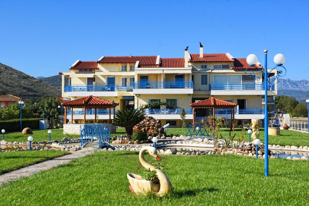 two swans in the grass in front of a building at Akrogiali in Myloi