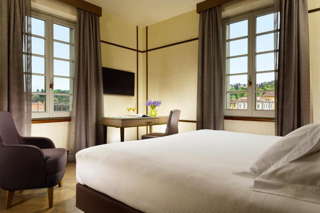 a hotel room with a bed and a desk and windows at Hotel Balestri - WTB Hotels in Florence