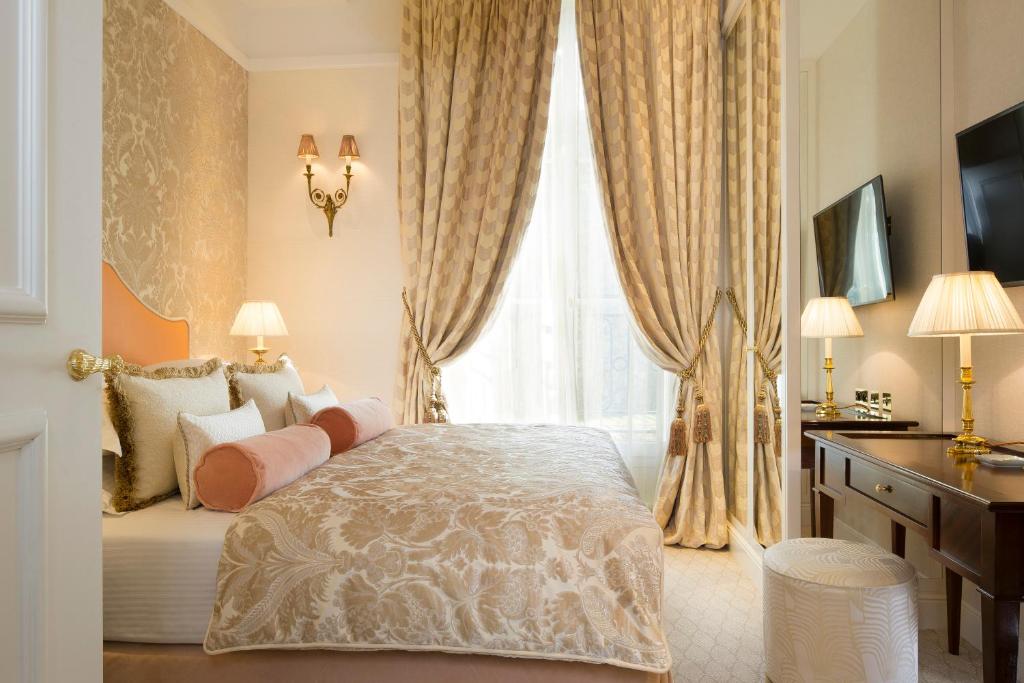 a bedroom with a bed and a desk and a window at Relais Christine in Paris