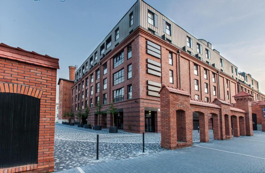 un gran edificio de ladrillo con un patio delante de él en P&J Apartments Lubicz en Cracovia