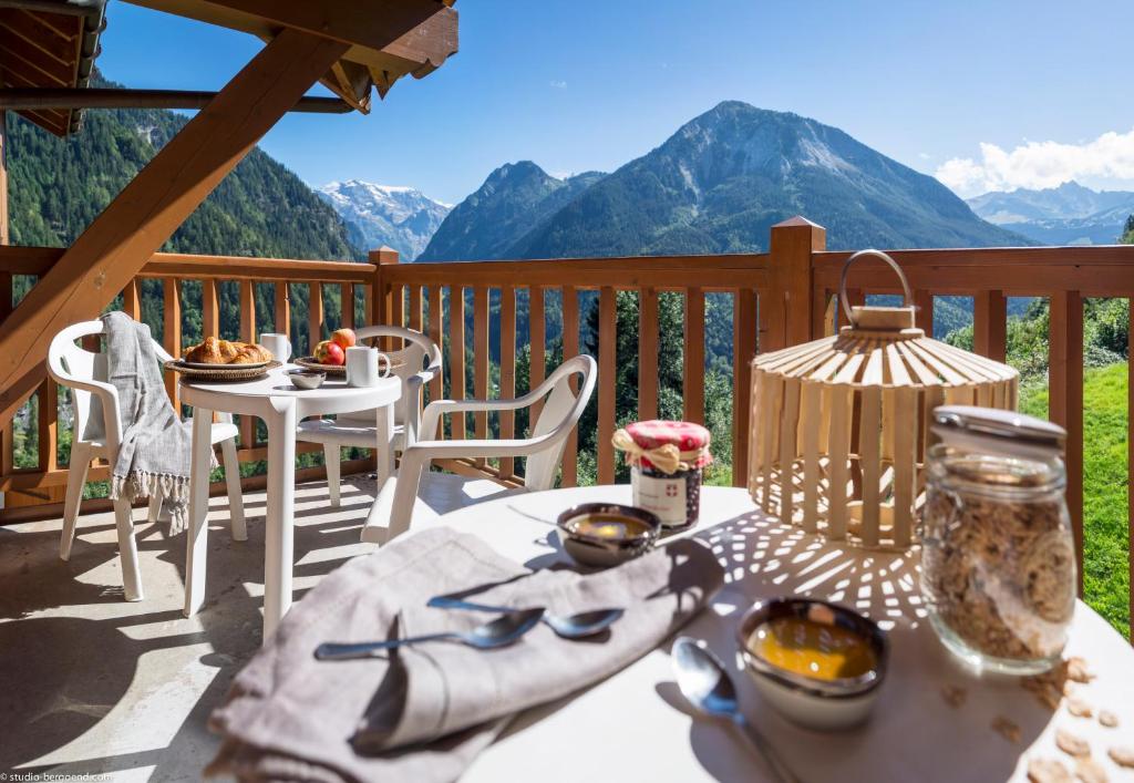 una mesa y sillas en una terraza con vistas a las montañas en Résidence Les Alpages De Champagny, en Champagny-en-Vanoise