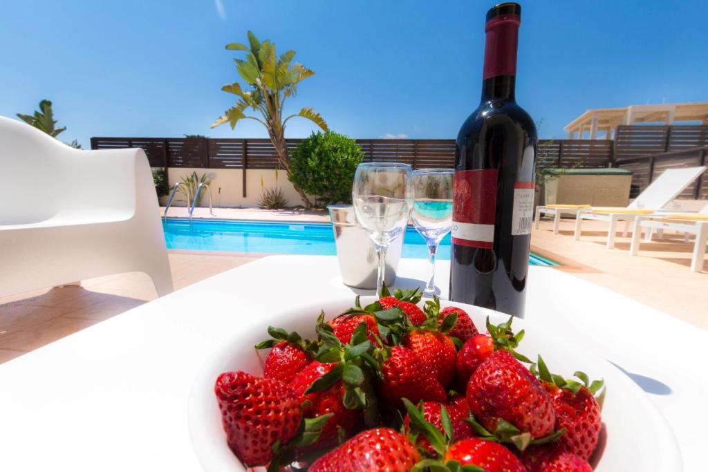 a plate of strawberries and a bottle of wine at Casa Di Kappari in Protaras