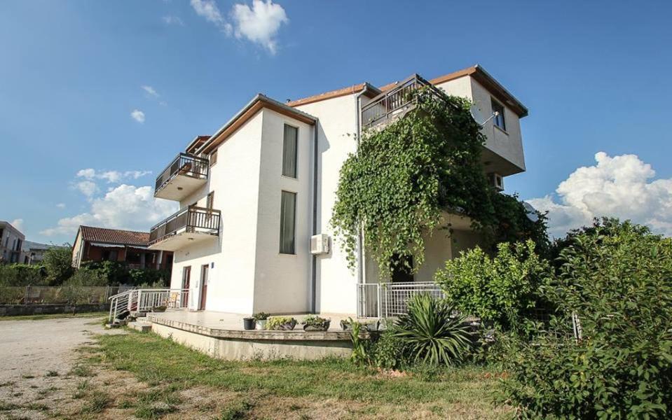 een wit huis met klimop aan de zijkant bij Apartments&Room Babic in Kaštela