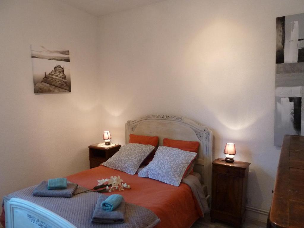 ein Schlafzimmer mit einem Bett mit orangefarbener Bettwäsche und zwei Lampen in der Unterkunft Appartement centre médiéval - Le Cosy de Sarlat in Sarlat-la-Canéda