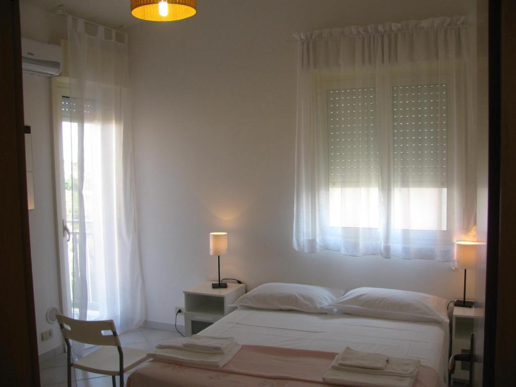 una camera bianca con un letto e una finestra di B&B Macalube Aragona ad Aragona
