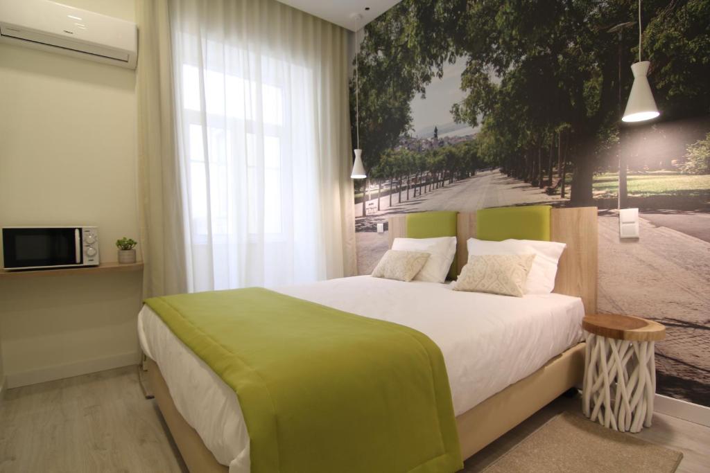 um quarto com uma cama grande e um cobertor verde em Páteo Saudade Lofts Marquês em Lisboa