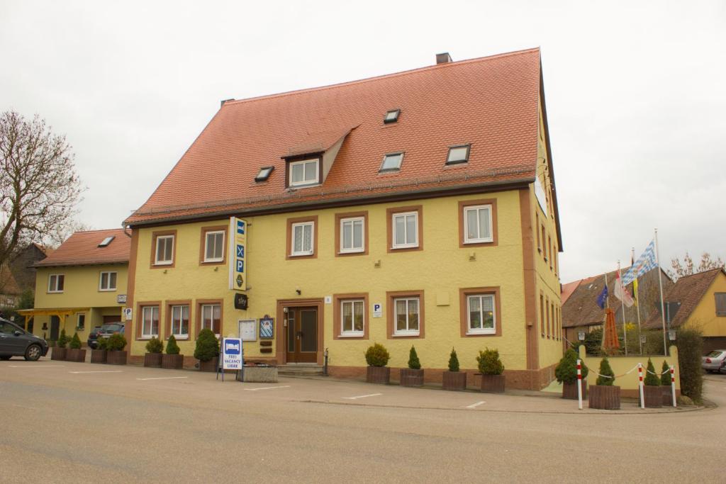 un bâtiment jaune avec un toit rouge dans une rue dans l'établissement Gasthof Neusitz, à Neusitz