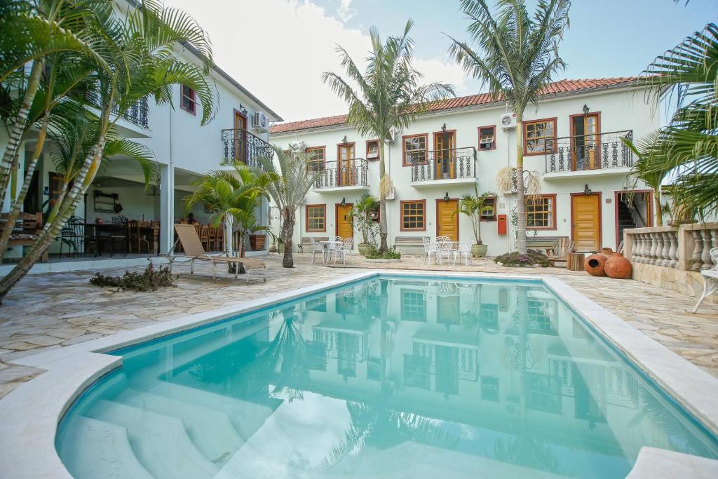 una piscina frente a una casa con palmeras en Pousada Neuza Barbosa, en Tiradentes
