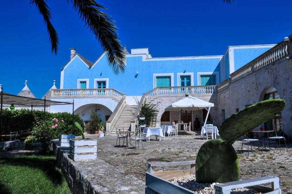 a white building with stairs and tables and chairs at Agriturismo Masseria Calongo in Cisternino