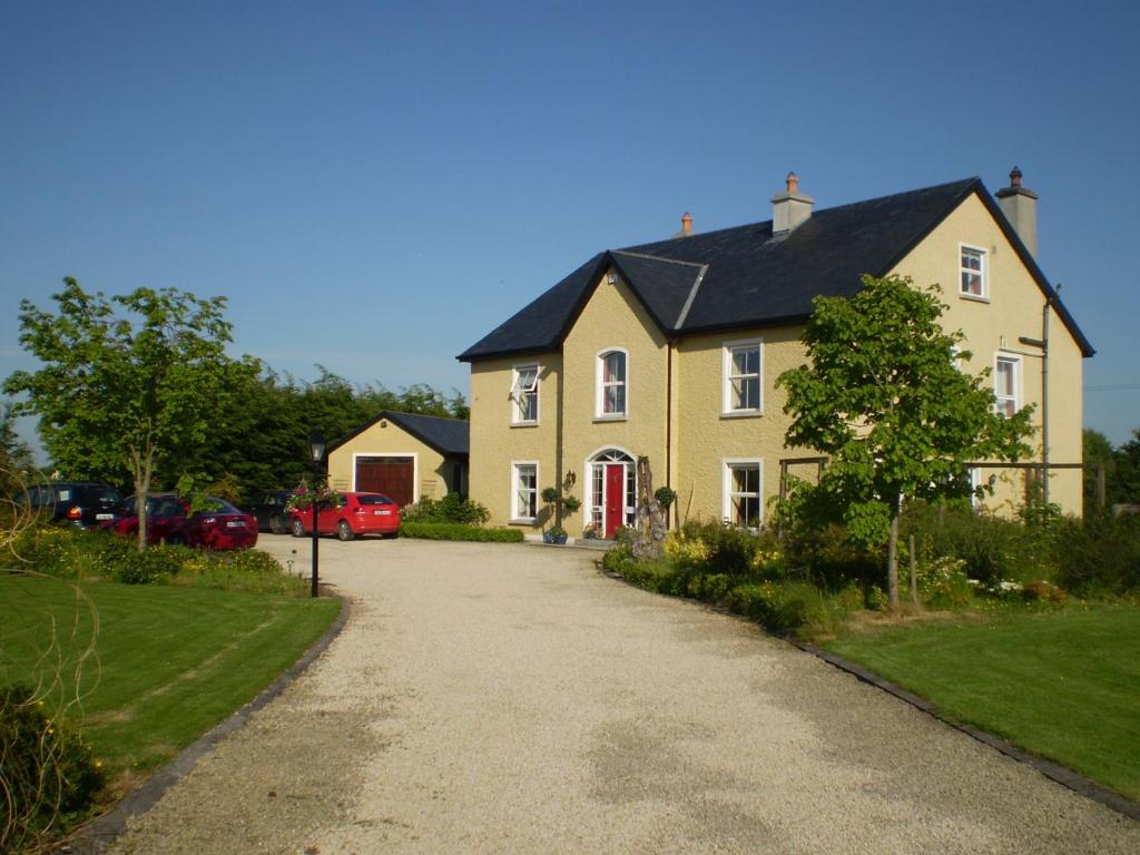 una casa amarilla con techo negro y entrada en Newlands Lodge, en Kilkenny