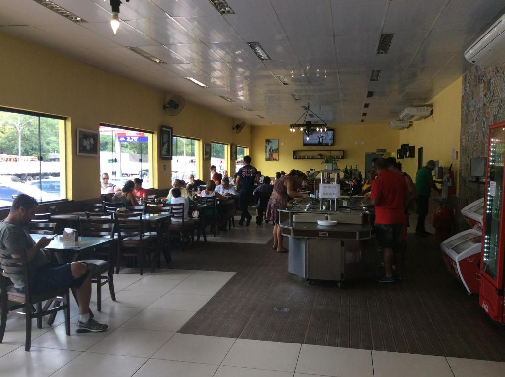 a dining room with people sitting at tables in a restaurant at Pousada Catavento in Piraí