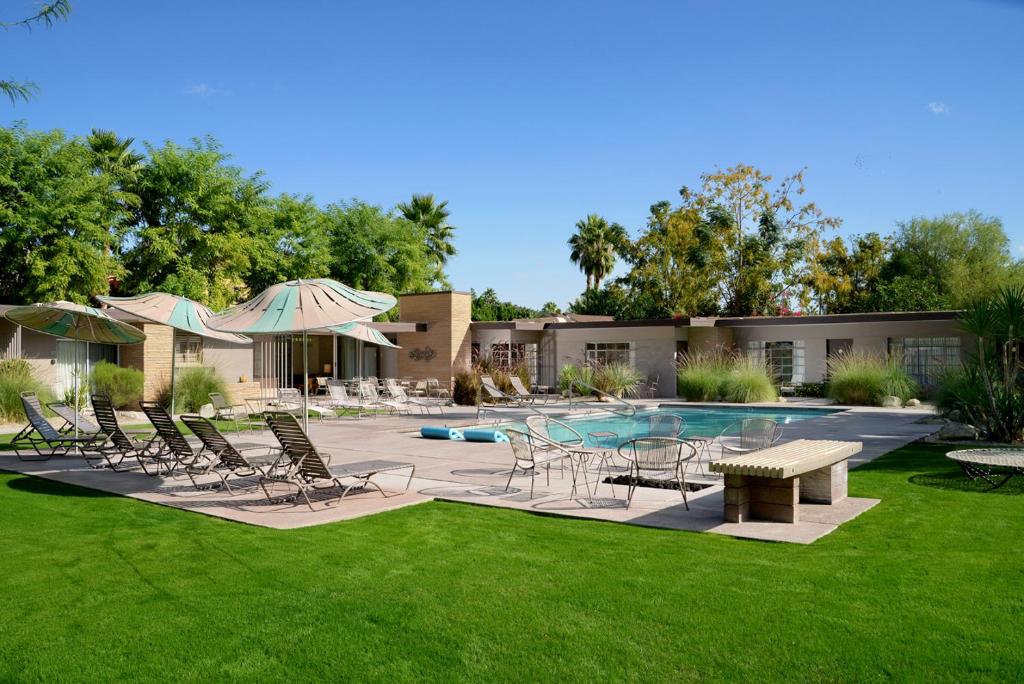a pool with chairs and a table and an umbrella at The Hideaway in Palm Springs