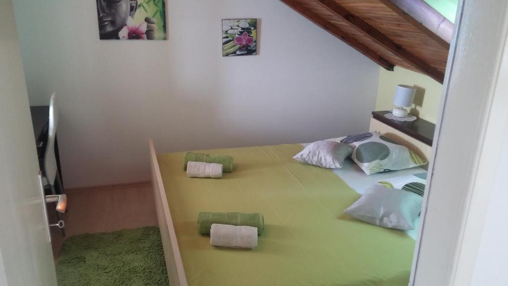 1 dormitorio con 1 cama verde y 2 almohadas en Apartments Benutic-Lalini, en Kaštela