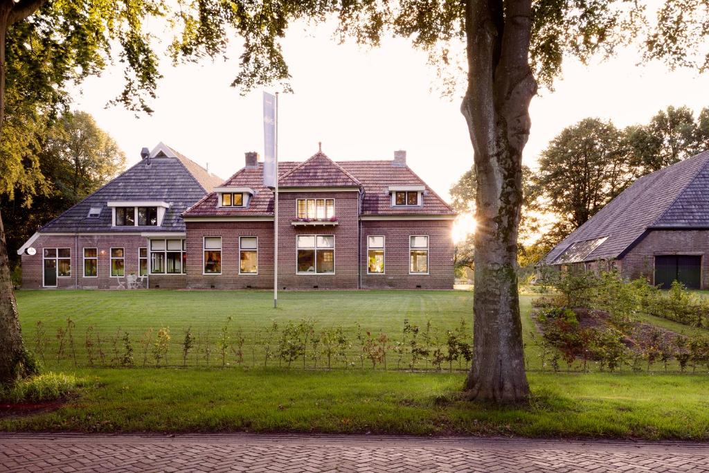 een groot huis op een grasveld met bomen bij Landhuis Hotel Rikus in Eext