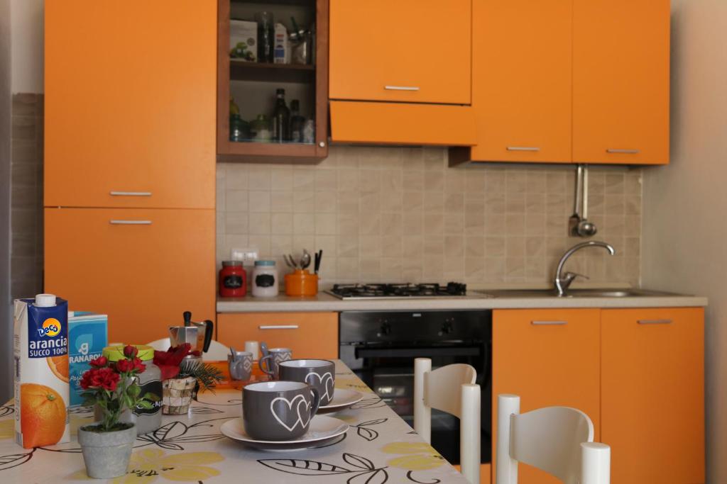 ドンナルカータにあるLa Casa di Marioのキッチン(オレンジ色のキャビネット、花のテーブル付)