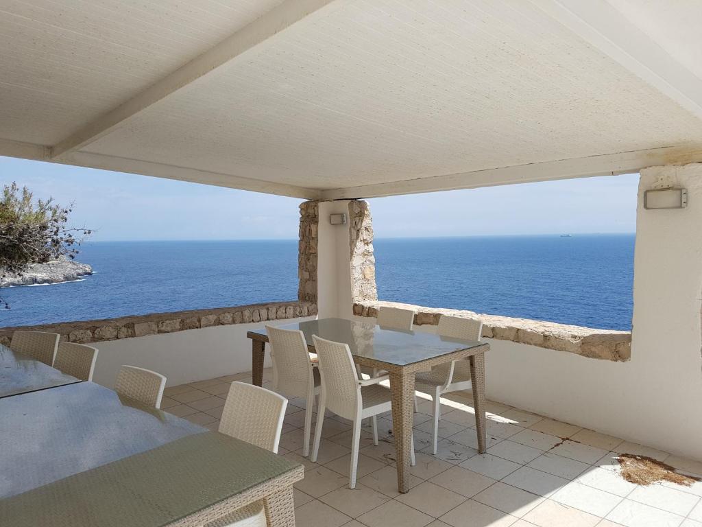 a table and chairs on a balcony with the ocean at Villa Bocca del Pozzo in Gagliano del Capo