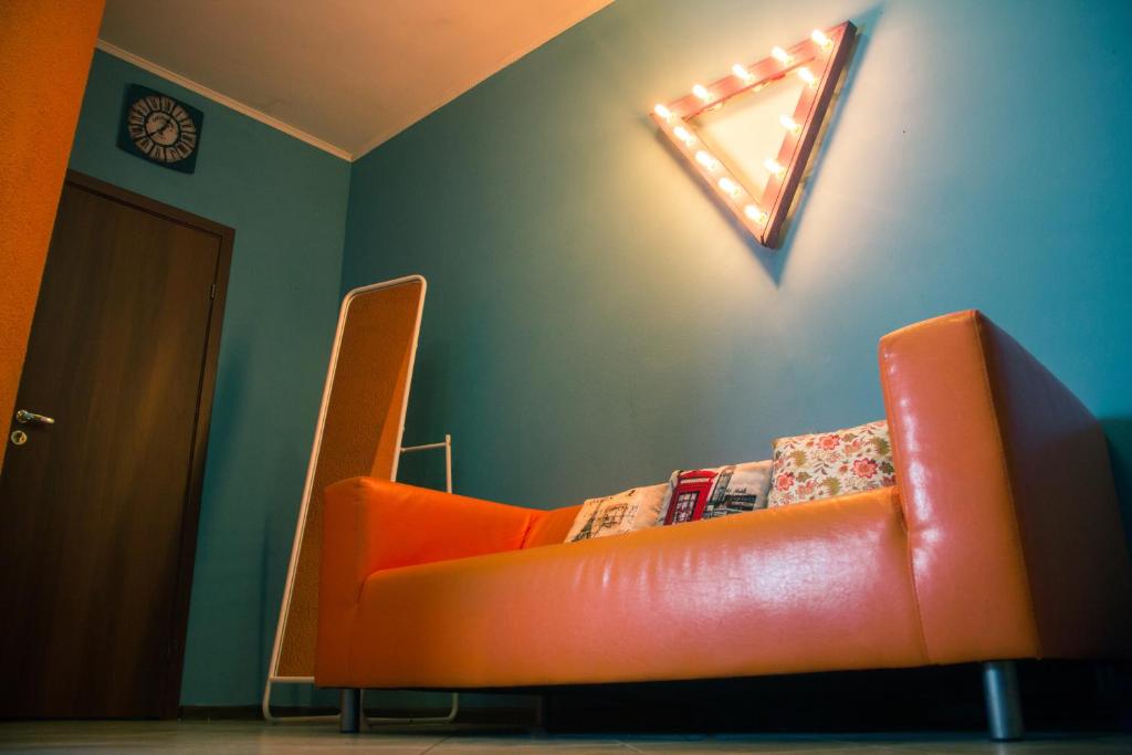 an orange couch in a room with a mirror at Rooms on Pirogova in Saint Petersburg