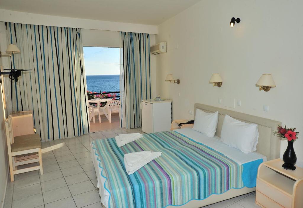 Creta Mare Hotel في بلاكاس: غرفة نوم مع سرير وإطلالة على المحيط
