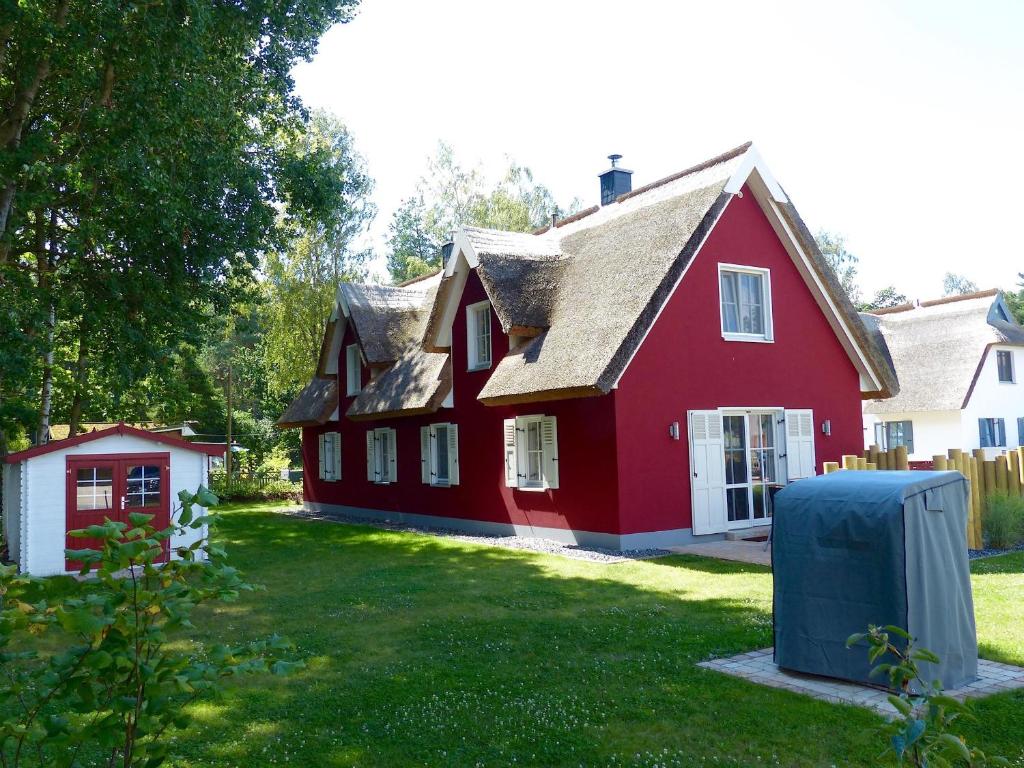 a large red house with a grass yard at Ferienhaus Greta in Glowe