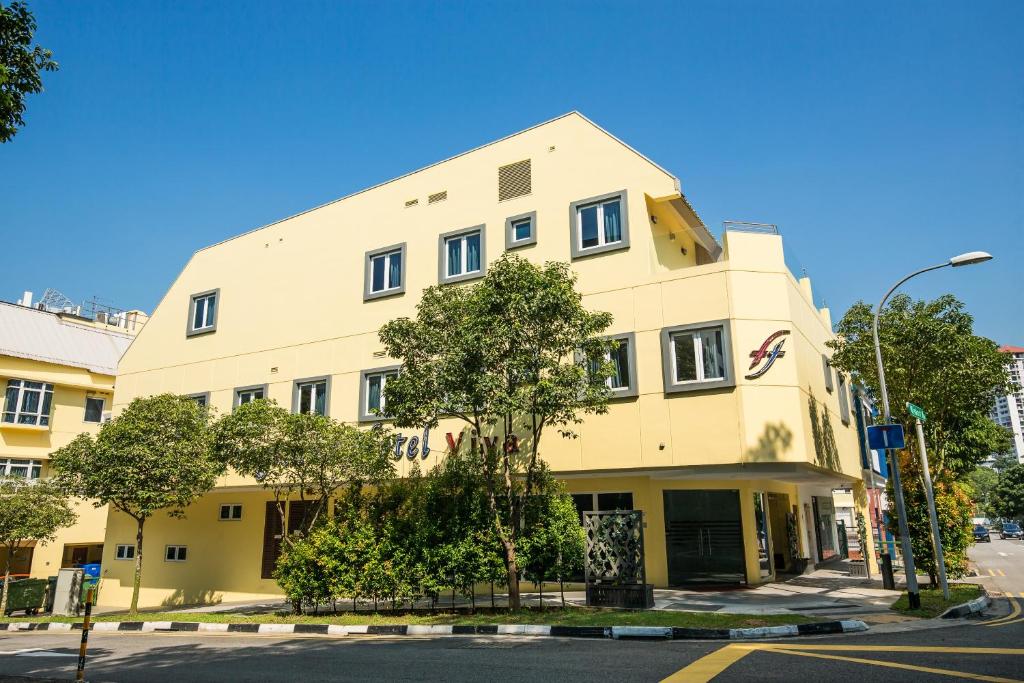 新加坡的住宿－Fragrance Hotel - Viva，前面有树的黄色建筑