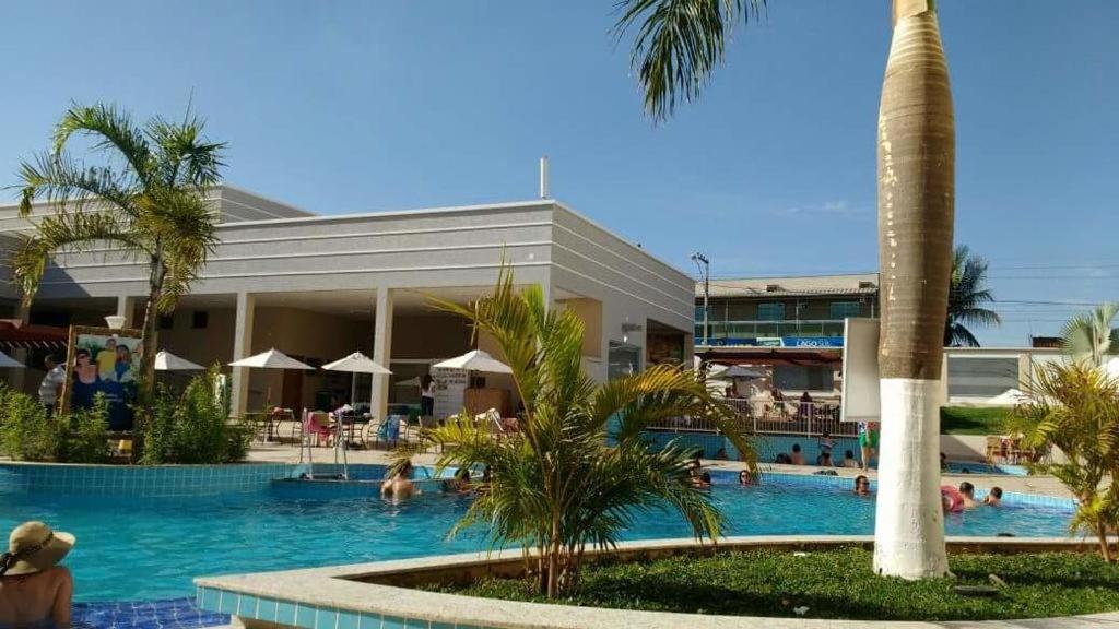 una piscina resort con palmeras y gente en ella en Apartamento no Encontro das Águas, en Caldas Novas