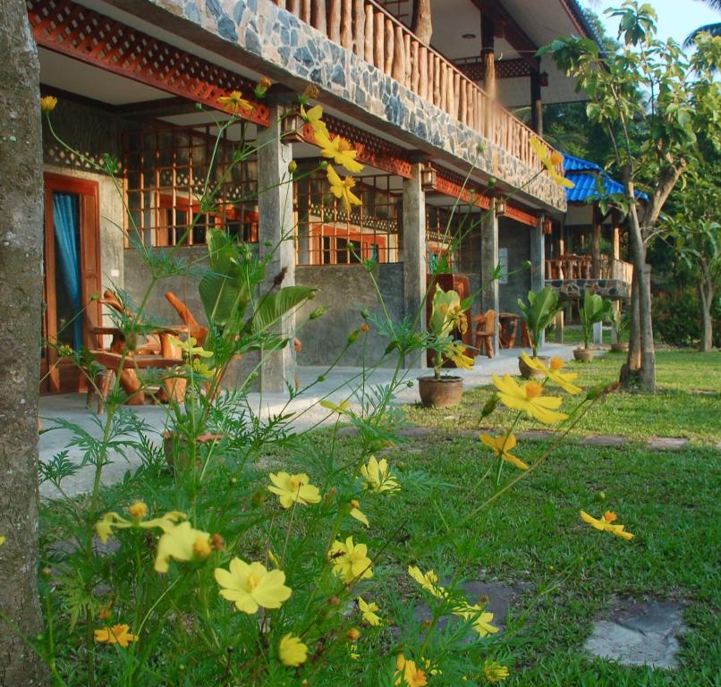 a building with flowers in the grass in front of it at Wonderland Healing Center in Thongsala