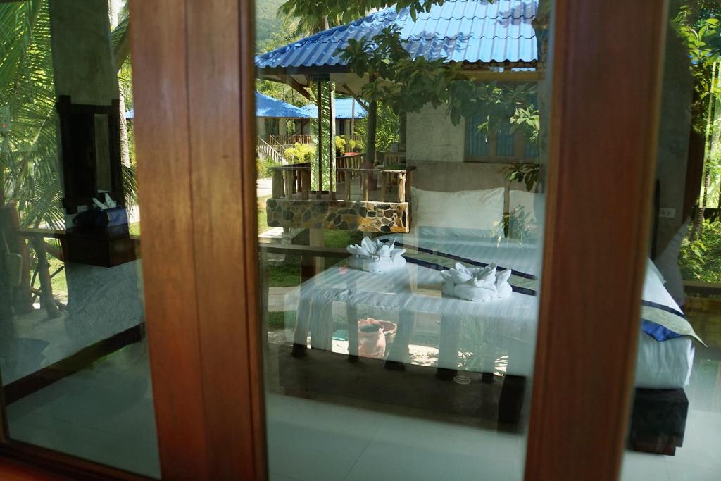 a view of a bedroom with a bed through a glass door at Wonderland Healing Center in Thongsala