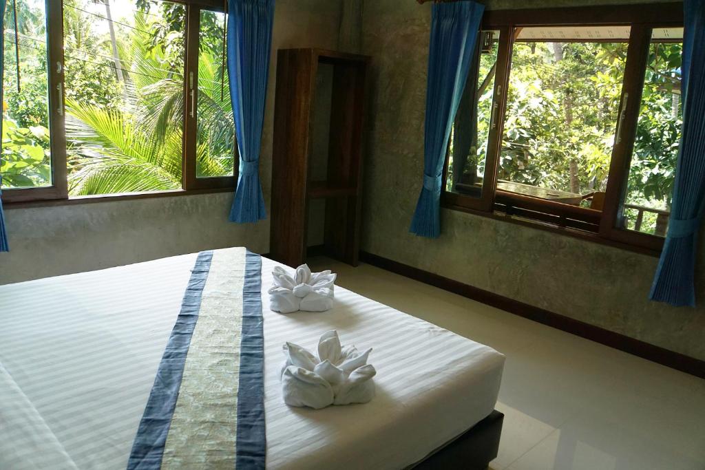 a bedroom with a bed with two white towels at Wonderland Healing Center in Thongsala