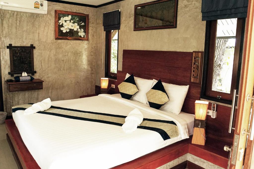 a bedroom with two beds and two windows at Wonderland Healing Center in Thongsala